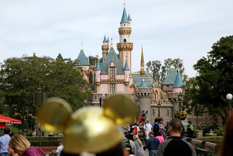 FILE - In this Jan. 22, 2015, file photo, visitors walk toward Sleeping Beauty's Castle in the background at Disneyland Resort in Anaheim, Calif. Disneyland says it's closing its California parks starting Saturday over coronavirus concerns. For most people, the new coronavirus causes only mild or moderate symptoms. For some it can cause more severe illness. (AP Photo/Jae C. Hong, File)