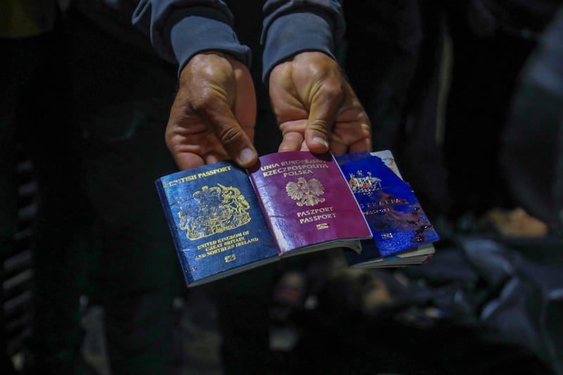 A man displays British, Polish and Australian passports next to the bodies of World Central Kitchen workers at Al Aqsa Hospital in Deir Al Balah, Gaza. AFP