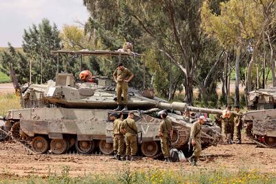 Israeli soldiers gather around army tanks stationed in an area along the border with the Gaza Strip in southern Israel. AFP