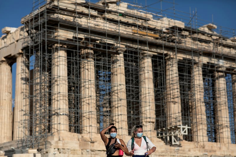 Two women wearing protective face masks amid Covid-19 pandemic visit the Parthenon temple atop the Acropolis hill in Athens.