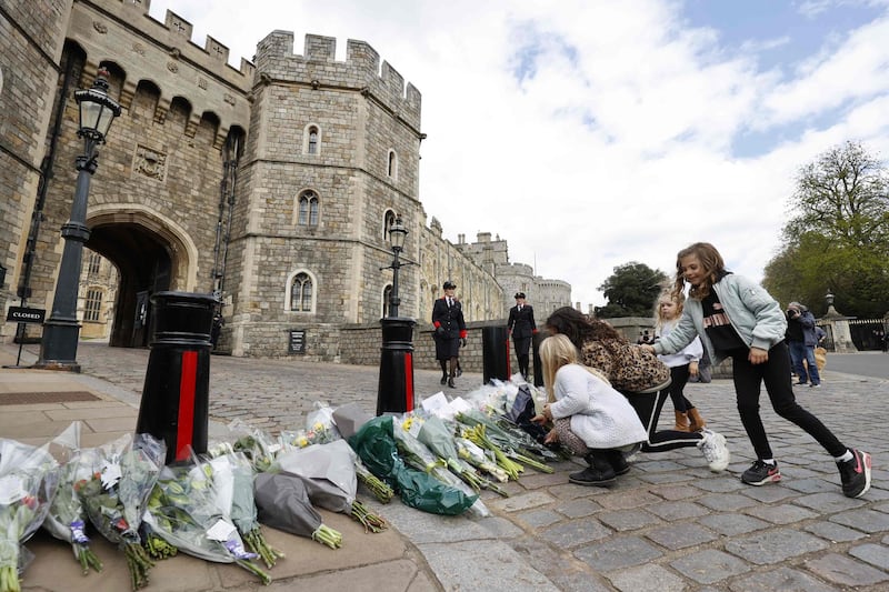 Children add to the floral tributes outside the Henry VIII Gate of Windsor Castle. AFP