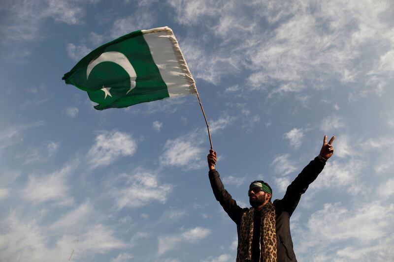 A supporter of Sufi cleric and leader of Minhaj-ul-Quran Muhammad Tahirul Qadri waves a Pakistan flag upside down as he takes part in the second day of a protest in Islamabad January 15, 2013. Pakistani security forces fired in the air and used tear gas in the capital Islamabad on Tuesday to try and control protests led by an anti-government cleric who is believed to be backed by the military. Qadri has brought tens of thousands of followers to the capital Islamabad to demand the resignation of top political leaders in the civilian government and electoral reforms to stamp out corruption. REUTERS/Zohra Bensemra (PAKISTAN - Tags: POLITICS RELIGION CIVIL UNREST) *** Local Caption ***  ZOH08_PAKISTAN-CLER_0115_11.JPG