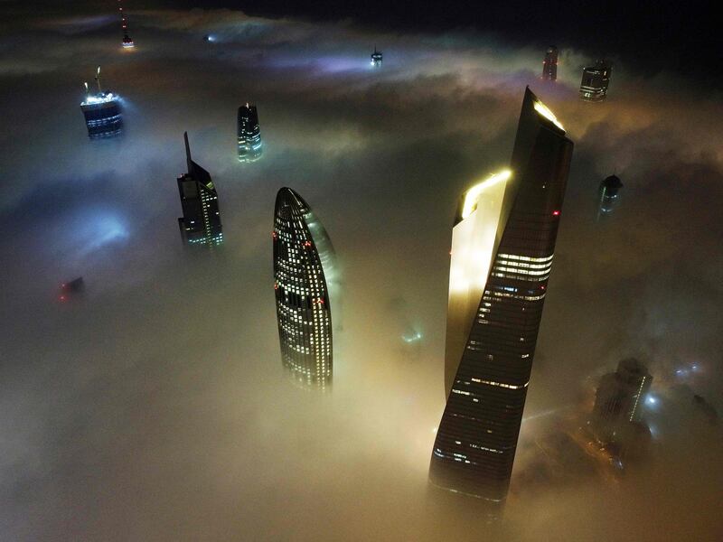 This aerial view shows Kuwait City's al-Hamra tower (R), the headquarters of The National Bank of Kuwait (C) and the al-Rayah tower (L), caught in heavy fog early on January 13, 2022.  (Photo by YASSER AL-ZAYYAT  /  AFP)