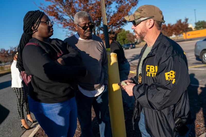 An FBI agent works to help people recover their cars from the scene. EPA