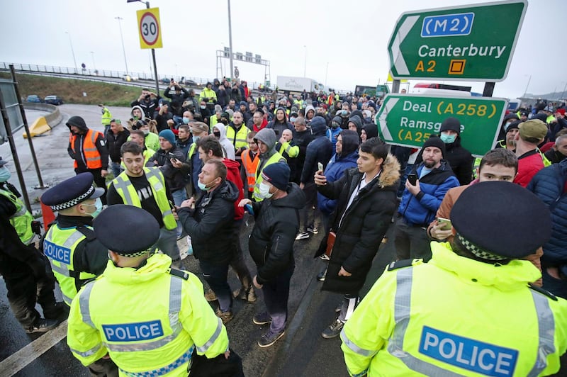 Truck drivers discuss with police holding them back at the entrance to the Port of Dover, in Kent, England. Freight from Britain and passengers with a negative virus test began arriving on French shores Wednesday, after France relaxed a two-day blockade over a new virus variant that had isolated Britain, stranded thousands of drivers and raised fears of shortages. AP