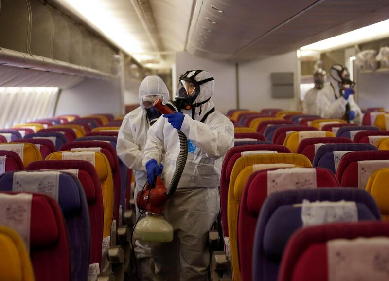 Thai technicians wearing protective suits spray disinfectant on passenger seats aboard a Thai Airways International aircraft.  EPA