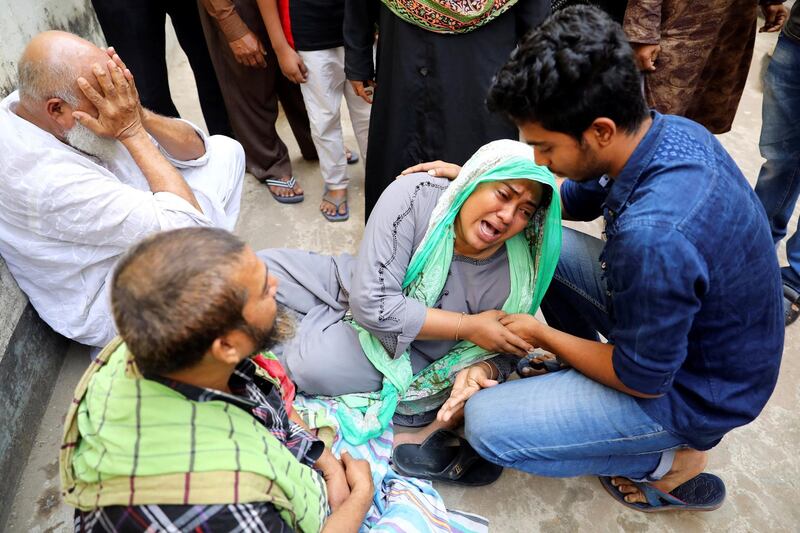 Unidentified relatives of victims mourn near the site of a burnt warehouse in Dhaka. Reuters
