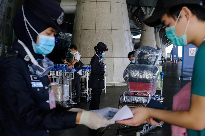 Airport police officers wearing protective masks check the documents of travellers at an entrance to Kuala Lumpur International Airport in Sepang, Selangor, Malaysia. Bloomberg