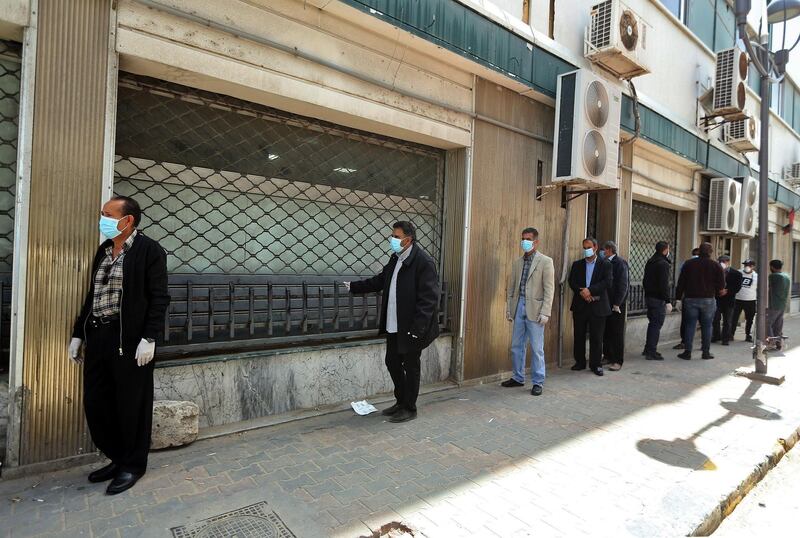 Libyans wearing protective face masks queue in front of a bank in the centre of the capital Tripoli amid the coronavirus pandemic.  AFP