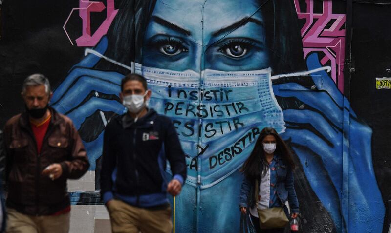 People in face masks are seen near a mural depicting a woman wearing a face mask in Bogota. AFP