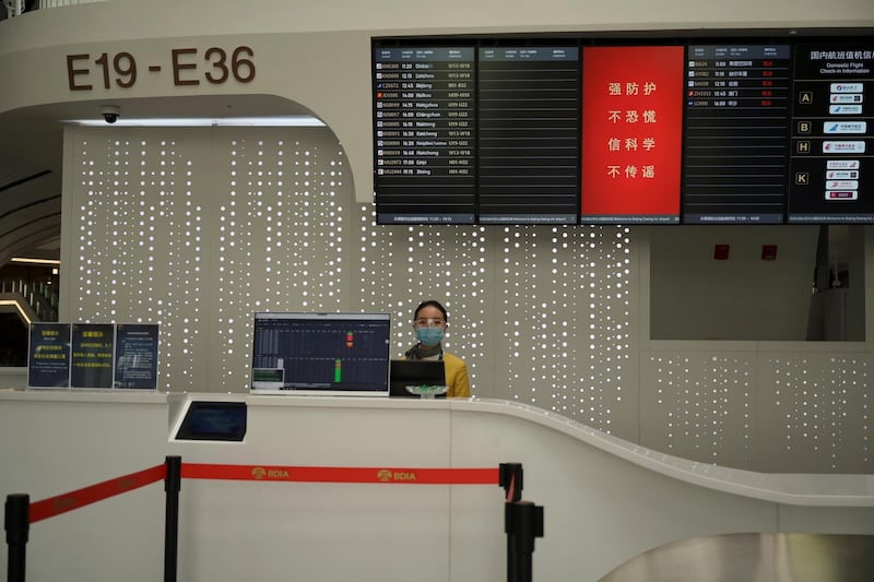 A staff member wearing face mask and goggles is seen at a counter at the Beijing Daxing International Airport, as the country is hit by an outbreak of the novel coronavirus, in Beijing, China February 20, 2020. REUTERS/Tingshu Wang