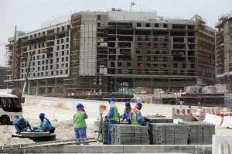 Abu Dhabi - March 2, 2009: Workers take a break in front of the a hotel construction site on Yas Island. ( Philip Cheung / The National ) *** Local Caption ***  PC0183-YasIsland.jpg