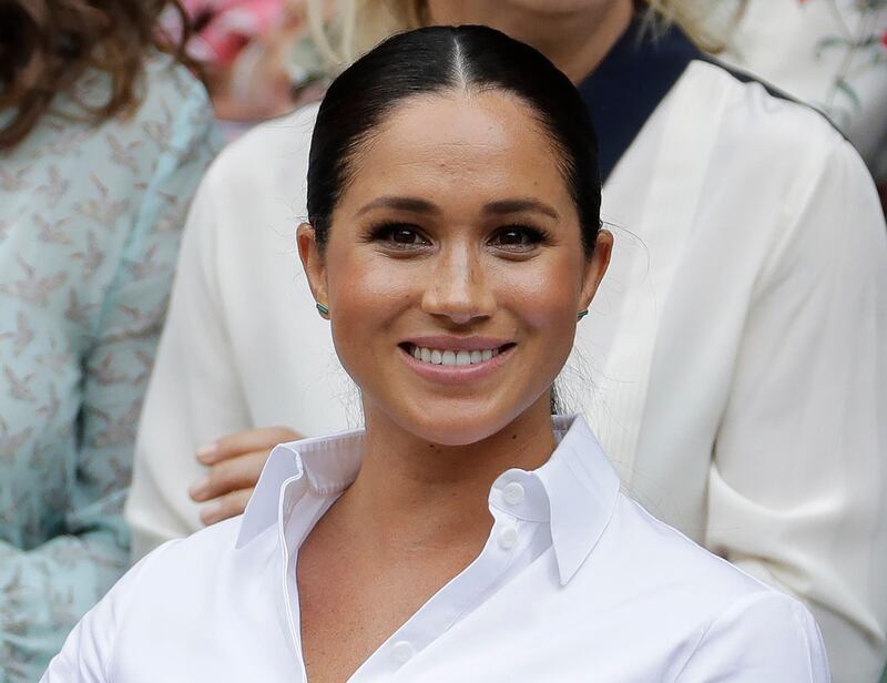 FILE - In this July 13, 2019 file photo, Kate, Meghan, Duchess of Sussex smiles while sitting in the Royal Box on Centre Court to watch the women's singles final match between Serena Williams, of the United States, and Romania's Simona Halep on at the Wimbledon Tennis Championships in London. Meghan has guest edited the September issue of British Vogue with the theme "Forces for Change." Royal officials say the issue coming out Aug. 2 features â€œchange-makers united by their fearlessness in breaking barriersâ€ and includes a conversation between Meghan and former U.S. first lady Michelle Obama.  (AP Photo/Ben Curtis, File)