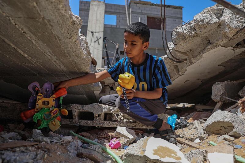 A Palestinian boy recovers his toys from the rubble of his house in Khan Yunis in the southern Gaza Strip. AFP