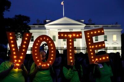 FILE - In this Oct. 6, 2018 file photo, Nancy McCullough, of Reston, Va., looks out the center of a letter "o" as she and other members of the group, Herndon Reston Indivisible, hold up letters spelling "vote them out" during a protest of the confirmation of Brett Kavanaugh to the Supreme Court outside of the White House in Washington. Brett Kavanaugh's confirmation is a flashpoint for the November midterms.  (AP Photo/Jacquelyn Martin, File)