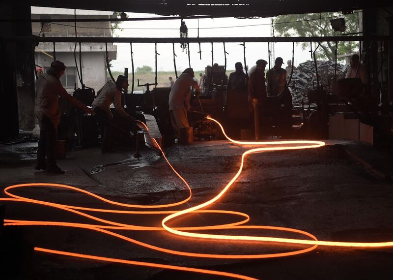 Pakistani labourers mould molten steel rods at a mill in Islamabad. Aamir Qureshi / AFP