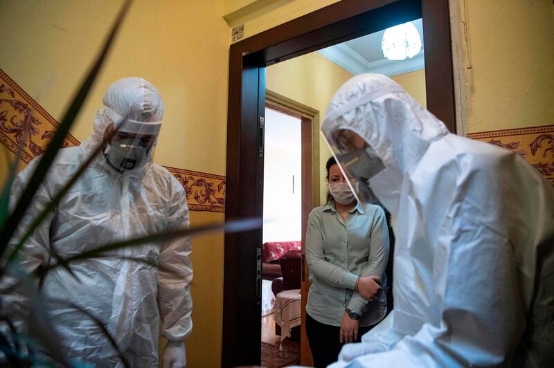 Health officer wearing protective clothing speak as they prepare before travelling to collect swab samples from confined people who are believed to have been in contact with coronavirus patients. AFP