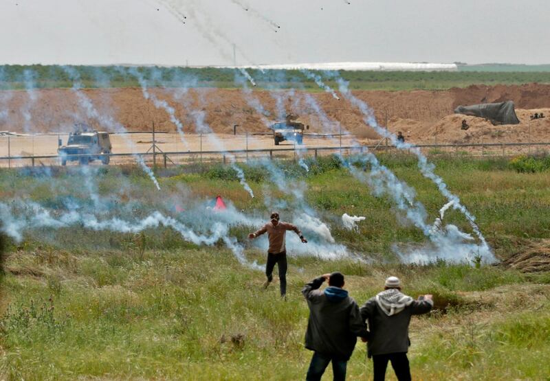 Palestinians flee as tear gas grenades begin to fall from the sky. Mahmud Hams / AFP Photo