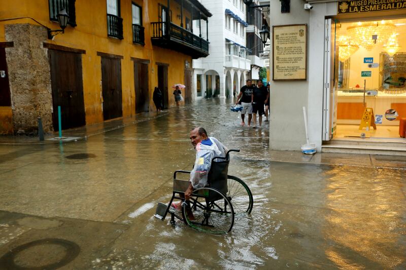 A man in a wheelchair moves through a flooded street after heavy rain in Cartagena, Colombia. EPA
