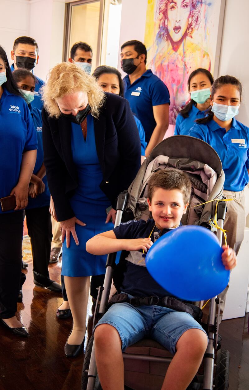 Sam with Gisele Clark (C), hotel manager at Hilton Dubai The Walk, and her staff, who dressed in blue for the day for the shoot, the colour associated with International Angelman Syndrome Day. 