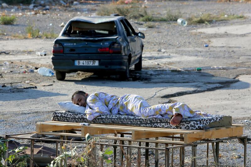A man sleeps near a damaged car near the site of Tuesday's blast in Beirut's port area. REUTERS