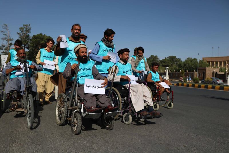 Afghan people, some on wheelchairs, holds pamphlets reading in Dari 'We want Peace' as they leave on a journey by foot to Kabul to cover a distance of around 1,800km, calling for an end to a decades-old war. EPA