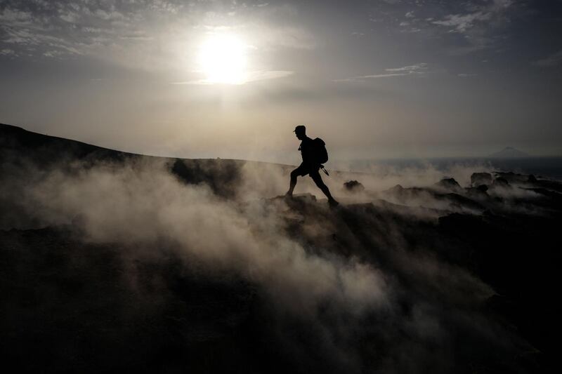 A tourist walks in the fumaroles of a crater on the volcanic island of Vulcano, one of the Aeolian Islands, in the Tyrrhenian Sea, Italy.   / AFP