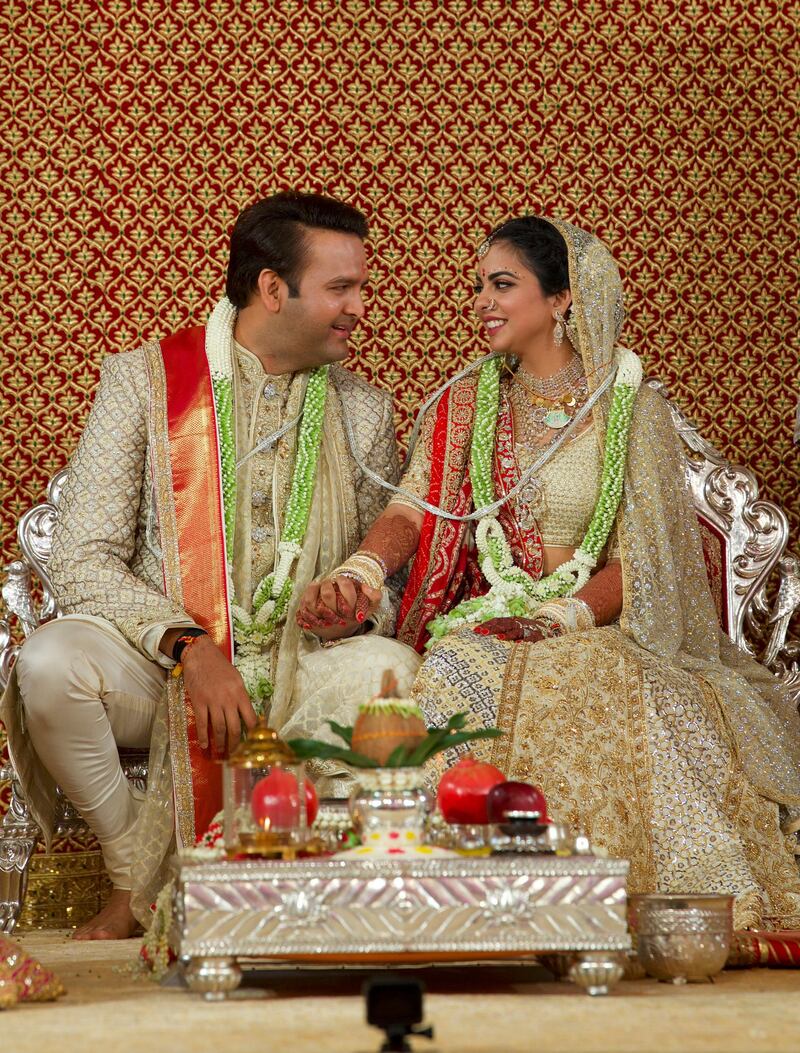 Newlyweds Isha Ambani, right, and Anand Piramal sit holding hands in Mumbai, India. AP Photo