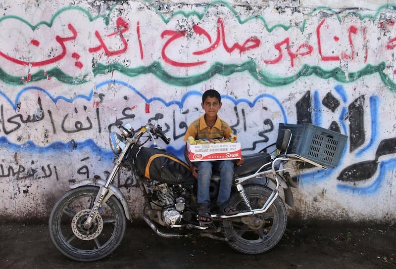 Twelve-year-old Palestinian boy Aref Moresh, who sells biscuit on the streets, poses for a photograph on a motorcycle in Gaza City. Mohammed Salem / Reuters