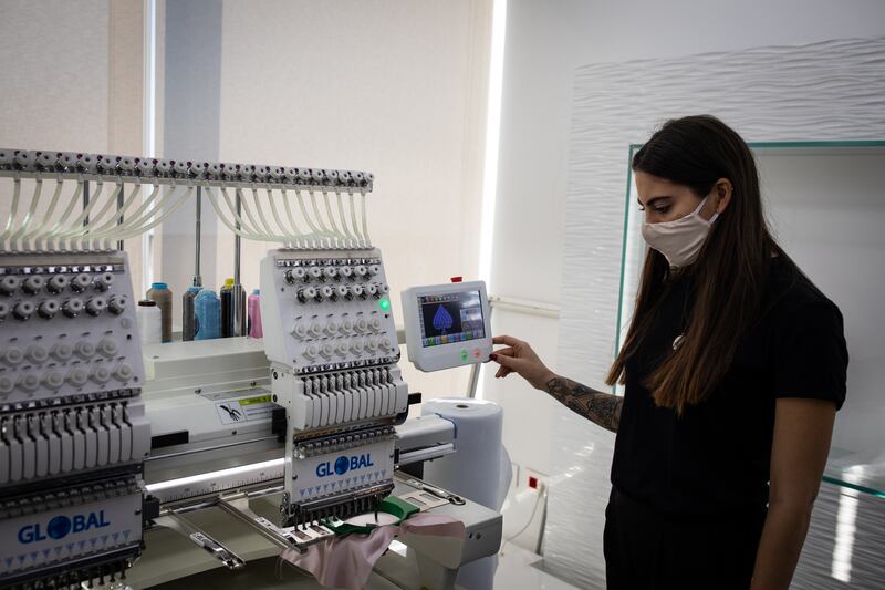 An employee of the Diamony Group operates the embroidery machine.