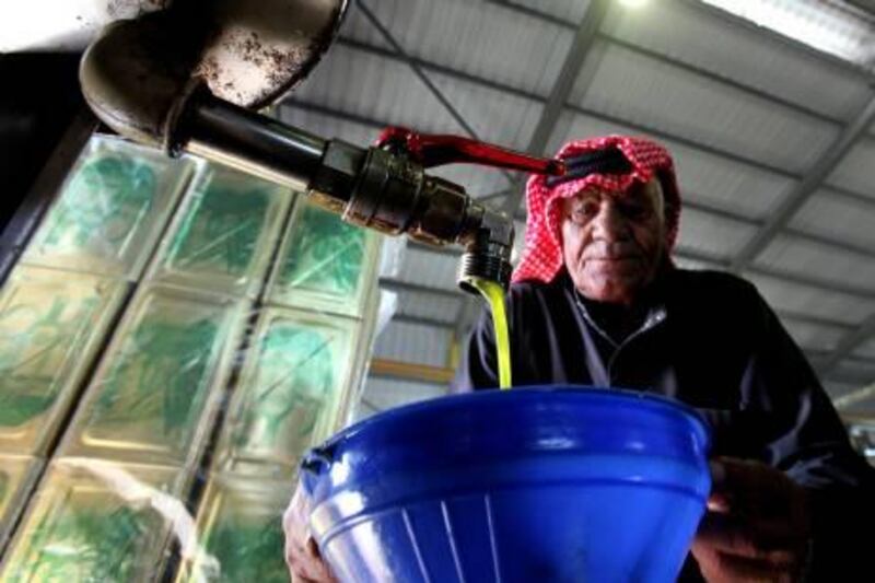 A Jordanian man controls the flow as olive oil pours into a container in a factory where olive oil is pressed in Salt city north west of Amman Saturday Oct. 31, 2009. The wild olive tree is believed to have originated in Asia Minor in the country known today as Turkey and is now common in the Mediterranean and Middle East. The oil has numerous uses and is commonly used in cooking although it can also be used in the pharmaceutical industry and in soaps.(AP Photo/Mohammad abu Ghosh) *** Local Caption ***  AMM101_Middle_East_JORDAN_OLIVE_OIL.jpg