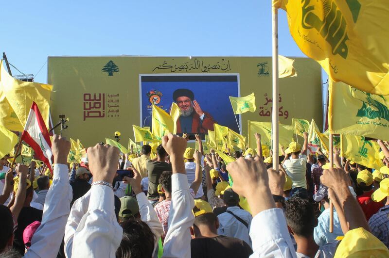 Supporters of the Lebanese Shiite militant movement Hezbollah wave th group's flag during a commemoration marking the 13th anniversary of the end of the 2006 war with Israel in the southern Lebanese town of Bint Jbeil on August 16, 2019. Hezbollah displayed a video showing a sample of its naval missiles, which was used 13 years prior to target an Israeli warship off the Lebanese coast during the July 2006 conflict. / AFP / Mahmoud ZAYYAT

