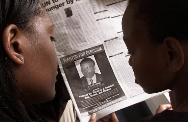FILE PHOTO: Readers look at a newspaper June 12, 2002 in Nairobi carrying the photograph of Rwandan Felicien Kabuga wanted by the United States. The United States published a "wanted" photograph in Kenyan newspapers of the businessman accused of helping finance the 1994 killings in Rwanda REUTERS/George Mulala/File Photo