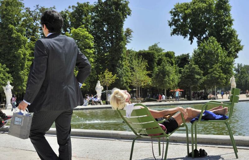 A man dressed in a suit walks past a woman enjoying a sun bath near the Tuileries fountains in central Paris. Philippe Wojazer / Reuters 