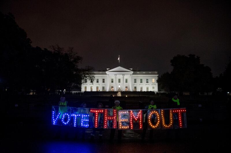 A group of people hold up a sign that reads "Vote Them Out" as they protest in front of the White House the night before midterm election voting begins in Washington. AP