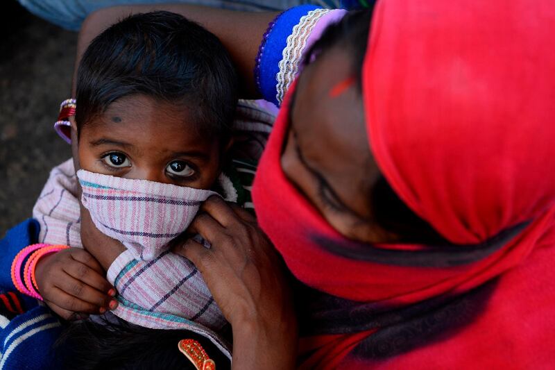 A mother covers her child's face with a cloth outside Anand Vihar bus terminal as they leave India's capital for their homes during a government-imposed nationwide lockdown as a preventive measure against the COVID-19 coronavirus, in New Delhi.   AFP