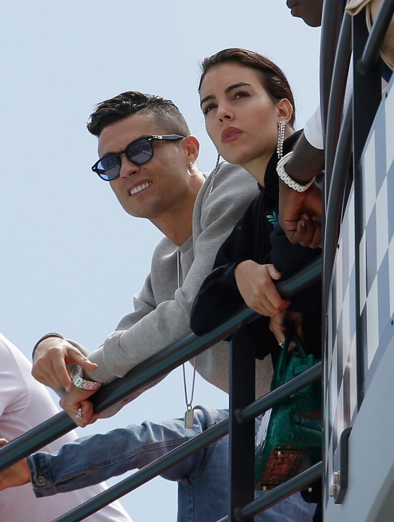 Cristiano Ronaldo, left, is flanked by his partner Georgina Rodriguez as they watch the second practice session at the Monaco racetrack, in Monaco, Thursday, May 23, 2019. The Formula one race will be held on Sunday. (AP Photo/Luca Bruno)