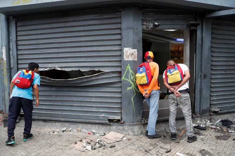 People look at the damage to a store after it was looted in Caracas. Reuters