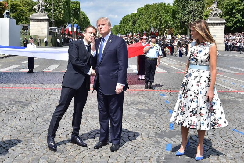 (FILES) In this file photograph taken on July 14, 2017, French President Emmanuel Macron (L) gestures as he shakes hands with US President Donald Trump (C) next to US First Lady Melania Trump, during the annual Bastille Day military parade on the Champs-Elysees avenue in Paris.
US President Trump has asked for a military parade to showcase US muscle and underscore his role as commander-in-chief, the White House said February 6, 2018. Trump, who has toyed with the idea of a parade in Washington since before being sworn in, has made the request to officers, who are looking for a date. / AFP PHOTO / POOL AND AFP PHOTO / CHRISTOPHE ARCHAMBAULT