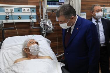 Turkey's Health Minister Fahrettin Koca speaks with Ahmet Citim, rescued from the debris of his collapsed house, in Izmir, Turkey. Turkey Health Ministry via AP