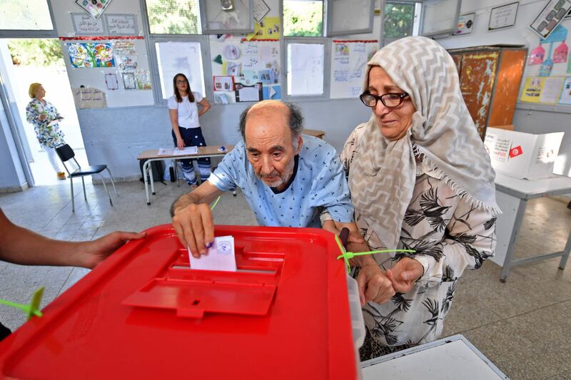 An elderly Tunisian man arrives with his wife to vote in a referendum on a draft constitution put forward by President Kais Saied, on July 25, 2022. AFP