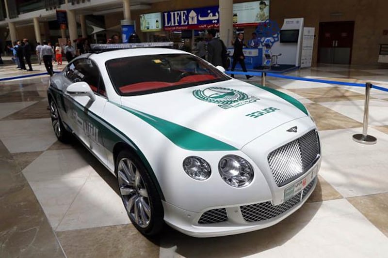 People walk past the new Dubai police Bentley patrol car on display during the Arabian Travel Market (ATM) at the Dubai World Trade Centre in the Emirati city on May 6, 2013. Dubai police have introduced top end sports cars to their patrol fleet to further strengthen the image of "luxury and prosperity" of the Emirate. AFP PHOTO/KARIM SAHIB