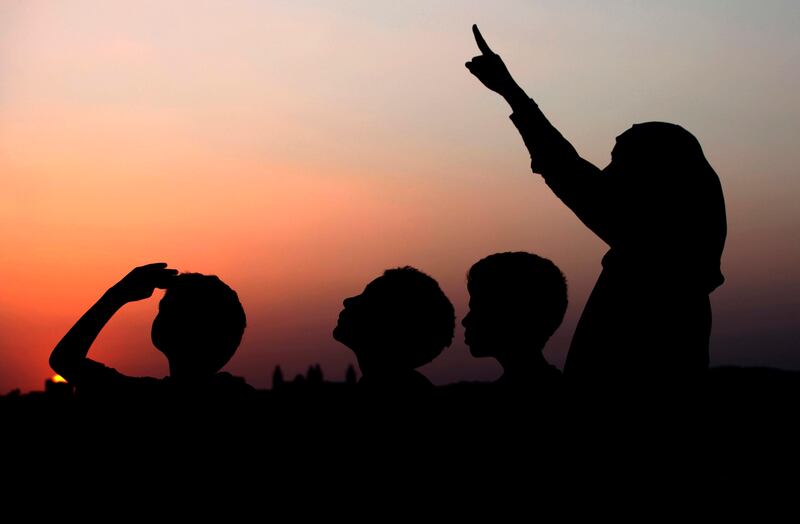 A woman points skyward as she and her sons look for the crescent moon in Amman, Jordan, at sunset Sunday, July 31, 2011. Religious authorities in most of the Middle East declared that Monday will be the start of the holy month of Ramadan, a period devoted to dawn-to-dusk fasting, prayers and spiritual introspection. Ramadan begins around 11 days earlier each year. Its start is calculated based on the sighting of the new moon, which marks the beginning of the Muslim lunar month that varies between 29 or 30 days. (AP Photo / Mohammad Hannon) *** Local Caption ***  Mideast Jordan Ramadan.JPEG-0cb71.jpg