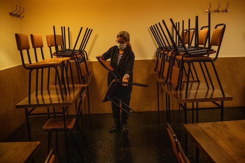 Gloria Hervella put chairs on tables at the Envalira Restaurant in Barcelona, Spain, before it closes under new restrictions to help fight the spread of coronavirus comes into force. Getty Images