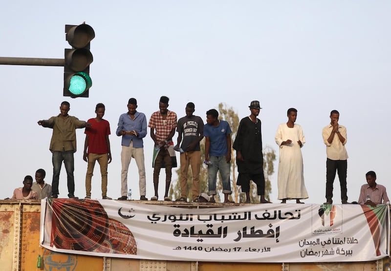epaselect epa07593161 A green traffic light is visible as Sudanese protesters stand on a blocked rail road bridge near at the site of a sit-in, near the Army Head quarters, in Khartoum, Sudan, 22 May 2019. The banner beneath the protestors reads in Arabic 'the revolutionary youth alliance, Ramadan fast breaking at the army HQ'. Sudanese protesters continue to flock to the sit-in site outside the army headquarters every evening, to share a Ramadan Iftar (fast break dinner), participate in debates, listen to various civil society speakers or discuss the political situation. The opposition groups and the army suspended their talk on early 21 May, as the alliance composed of protesters and opposition parties and the army disagreed on the control of the transition period. The opposition would like it  be a majority civilian run and say that the army would like it otherwise. Sudanese have started protesting in December 2018 against  the rule of former President  Hassan al-Bashir who resigned on 11 April.  EPA/AMEL PAIN  EPA-EFE/AMEL PAIN