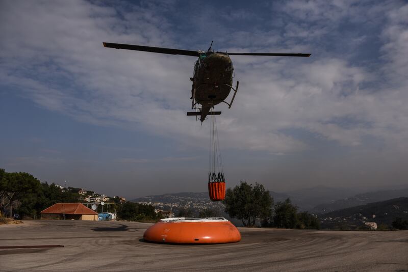 A helicopter picks up water to douse areas fire trucks can't reach at the Deir Al Kalaa monastery, near the town of Beit Mery.