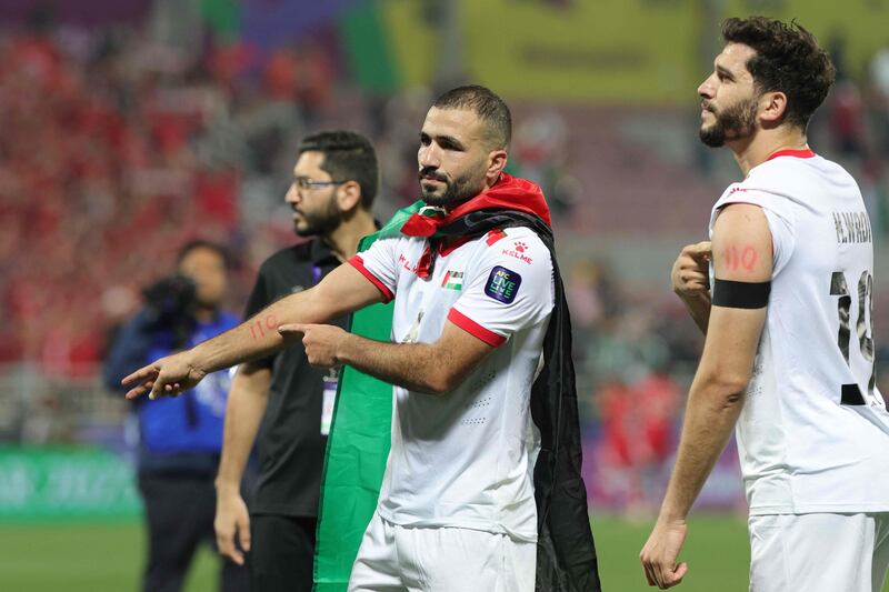 Palestine's Oday Kharoub and Mahmoud Wadi point to the number 110 on their arms, as they display support with the people of Gaza, during the Asian Cup match against Hong Kong. AFP