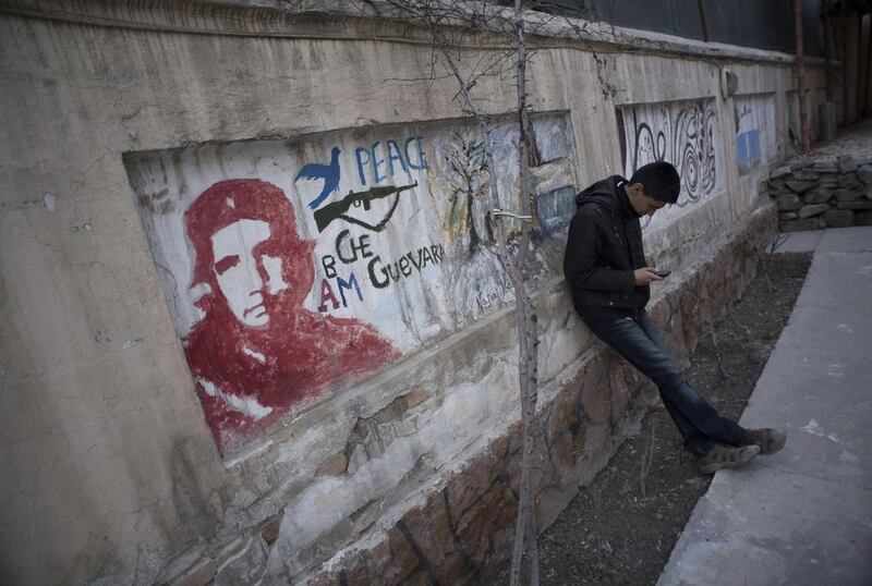 An art student uses his mobile phone as he stands next to graffiti on a wall at a cultural and educational centre in Kabul on March 7, 2014. Morteza Nikoubazl / Reuters