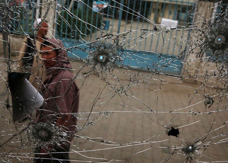 People look at a cracked side window of a bus which was damaged at bomb blasts in Kabul. Abdullah Abdullah, front-runner in Afghanistan’s presidential election, escaped assassination on Friday when two bombs blew up outside a hotel where he had just staged a rally, killing six people. Ahmad Masood / Reuters