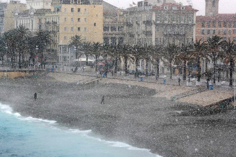 People walk through heavy snowfall along the Promenade des Anglais on February 26, 2018 in Nice. Valery Hache / AFP